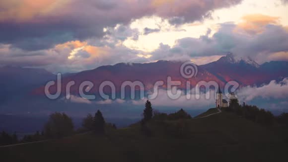 斯洛文尼亚杰姆尼克的日落空中无人机俯瞰阿尔卑斯山和圣普里莫兹教堂视频的预览图