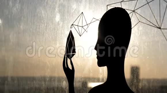 女性黑色的轮廓靠在玻璃窗上手里拿着一个奇怪的物体库存录像阳光透过视频的预览图