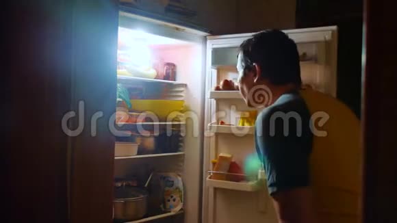 人们晚上从冰箱里吃饥饿和饕餮男人晚上看冰箱生活方式暴食视频的预览图
