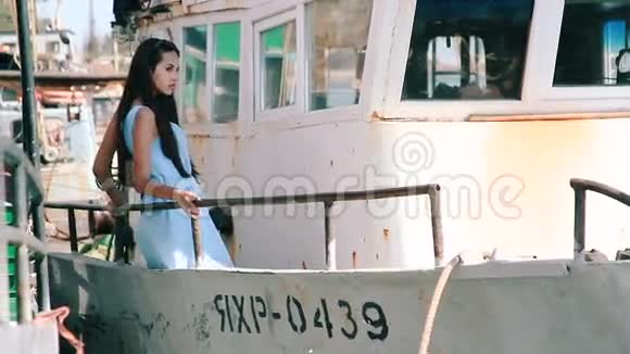 在旧船尾的年轻女孩在商船上摆姿势的女孩布鲁内特在船上肖像视频的预览图