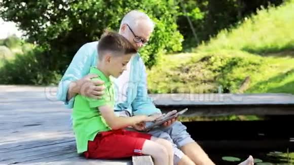 祖父和男孩带着平板电脑在河泊35号视频的预览图