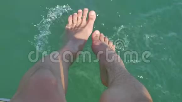 人们的双腿从帆船游艇上溅起海水在炎热的夏日在码头上用水浸脚视频的预览图
