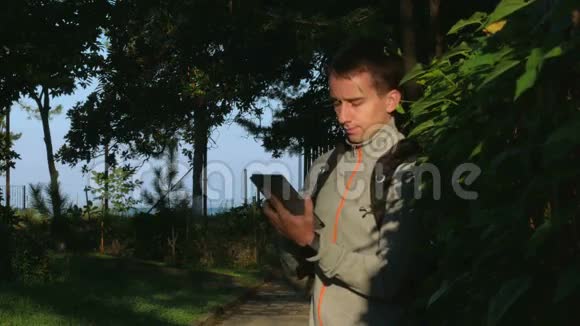 一个人站在公园里日出时手里拿着平板电脑它对社会网络上的帖子作出回应视频的预览图