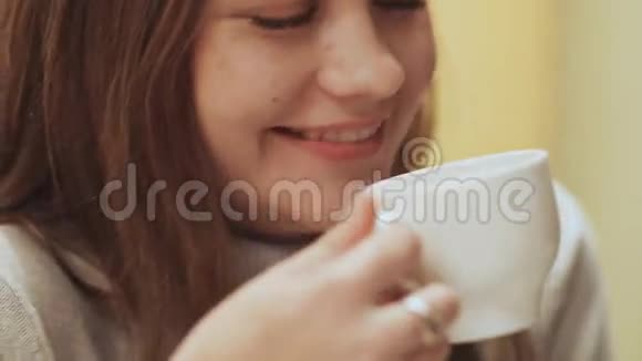 年轻漂亮女学生的特写脸喝着一杯咖啡视频的预览图