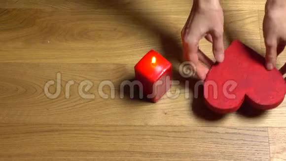 女人的手把两个红色的心形放在蜡烛附近爱情浪漫情人节聚会家庭约会视频的预览图