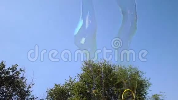 巨大的长肥皂泡在天空中飞舞两个用来制造气泡的装置视频的预览图