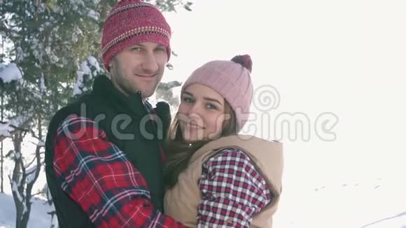 一对年轻可爱的夫妇的肖像在一个阳光明媚的冬天的森林里视频的预览图