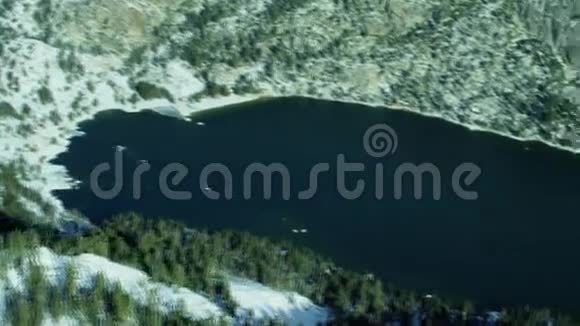 冬季雪松林山之间的湖顶空中4k镜头视频的预览图