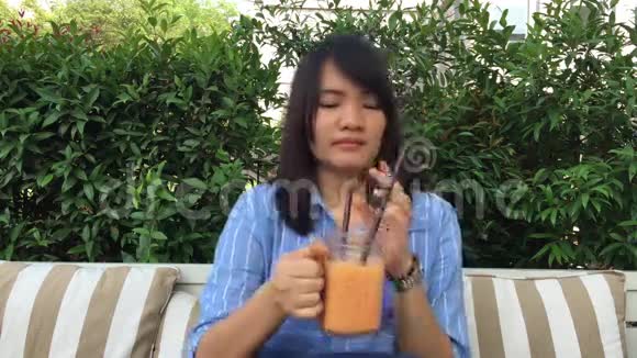 女人在玻璃杯里用管子喝茶视频的预览图