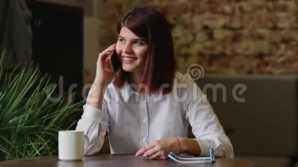 幸福的年轻女人坐在沙发上穿着舒适的衣服喝着咖啡视频的预览图