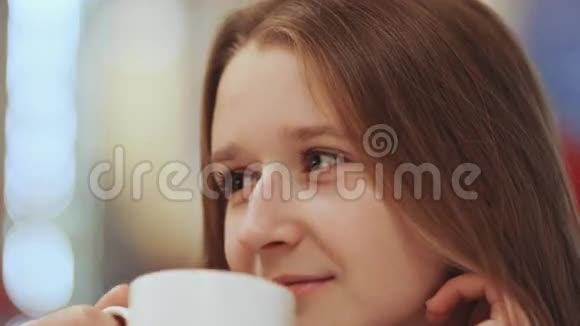 年轻漂亮女学生的特写脸喝着一杯咖啡视频的预览图