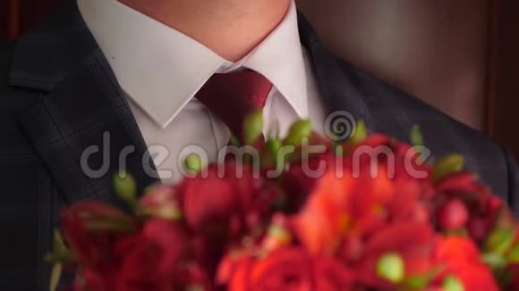 穿着红色领带和白色衬衫的男人手中捧着一束美丽的红玫瑰美丽的花束视频的预览图