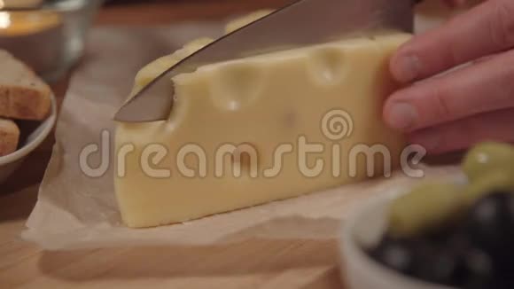 女人在木制烹饪板上切奶酪女人切奶酪视频的预览图