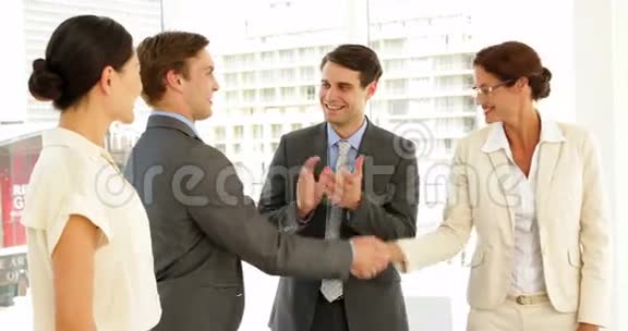 商务人士在面试时握手而其他人则鼓掌视频的预览图