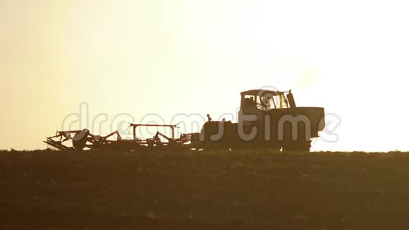 俄罗斯拖拉机夕阳农民剪影以播种机为一部分的土壤改良土地视频的预览图