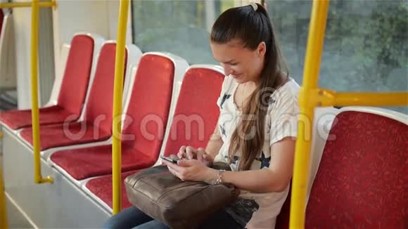 美丽的年轻女子乘坐城市交通工具使用她的手机女性在公共场合使用智能手机视频的预览图