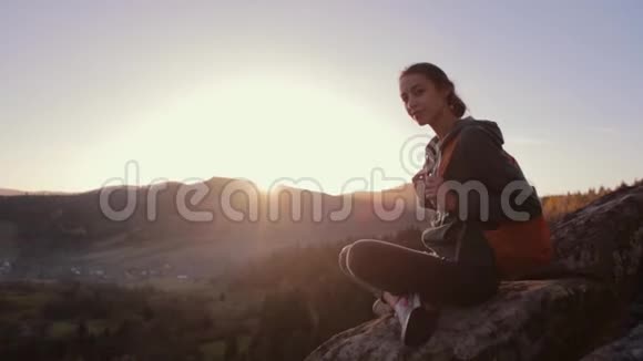 在日出的背景下女人坐在悬崖边视频的预览图