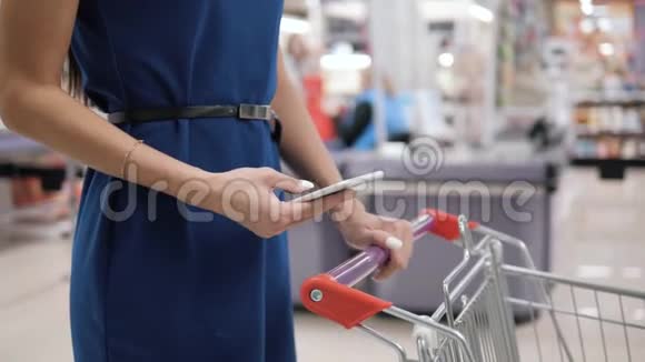 在超市购物时使用手机的女人在购物中心购物店购物视频的预览图