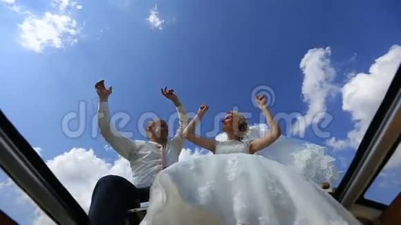 快乐的年轻快乐的新婚夫妇在复古的公共汽车顶部跳舞挥舞着手和腿下面的视图视频的预览图