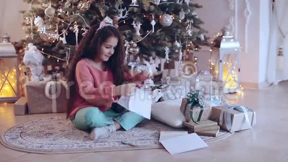 圣诞快乐假日快乐可爱的小女孩在圣诞树附近给圣诞老人写信视频的预览图