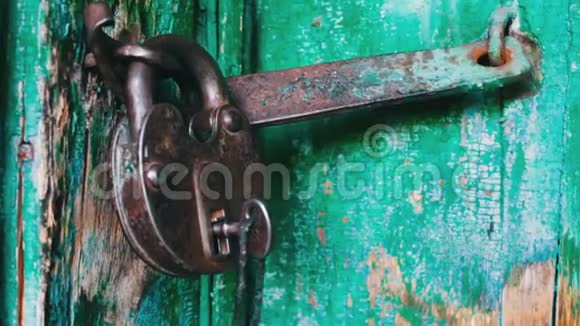 旧的老式铁锁在门上绿色油漆剥落把钥匙插在里面闭着眼睛视频的预览图