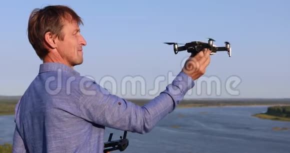 一名男子发射四架直升机阳光明媚的一天在河和森林上空飞行的无人机视频的预览图