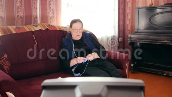家里的老太太看电视和编织羊毛袜子的老太太视频的预览图
