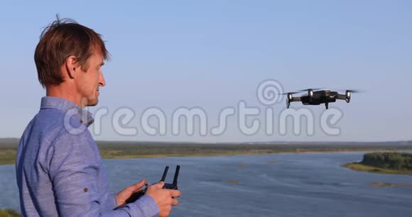 一名男子发射四架直升机阳光明媚的一天在河和森林上空飞行的无人机视频的预览图