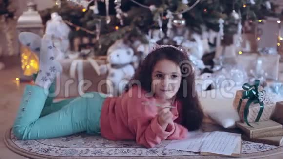 圣诞快乐假日快乐可爱的小女孩在圣诞树附近给圣诞老人写信视频的预览图