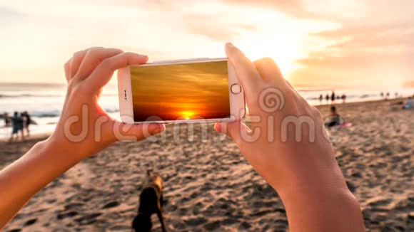晚上女人用智能手机在海滩上拍摄日出拍摄时效性的电影摄影风格视频的预览图