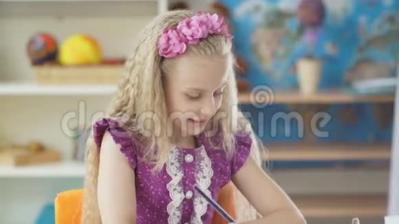 小女孩画了一支蓝色铅笔坐在书桌前画画的女孩视频的预览图