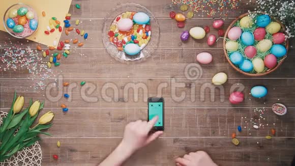 男人使用智能手机桌面上有绿色屏幕上面装饰着复活节彩蛋顶部视图视频的预览图