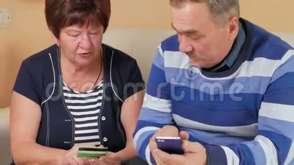 老年夫妇通过信用卡和电话在网上购物坐在家里的男人和女人的数据卡视频的预览图