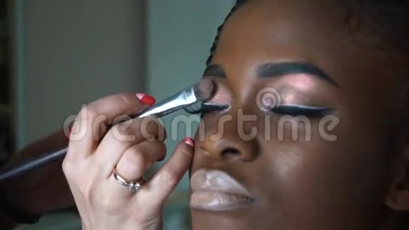 化妆师为美丽的非裔美国女孩做了一个明亮的妆容特写视频的预览图