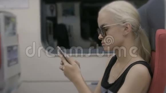 年轻疲惫的金发女郎在地铁列车上使用智能手机视频的预览图