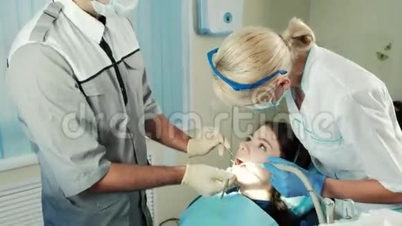 牙医用工具检查坐在椅子上的病人的下巴视频的预览图