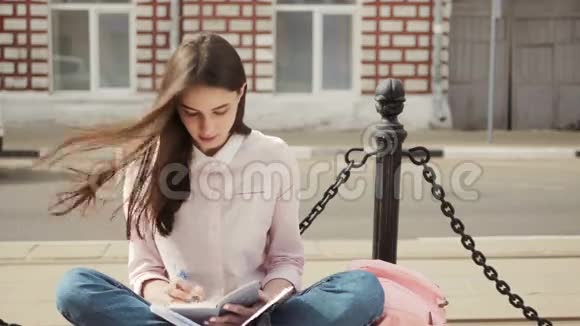 一个漂亮的十几岁的学生女孩坐在副本书和学习的肖像夏日阳光明媚现代和休闲视频的预览图