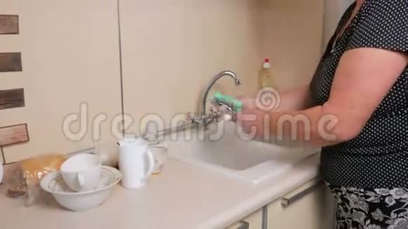 一个年老的女人在家里洗菜她轻轻地擦拭杯子和叉子海绵它用的是洗涤剂视频的预览图
