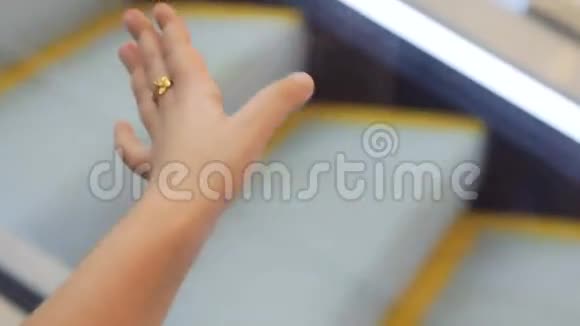 小女孩手上的特写镜头手里拿着自动扶梯在购物中心降落视频的预览图