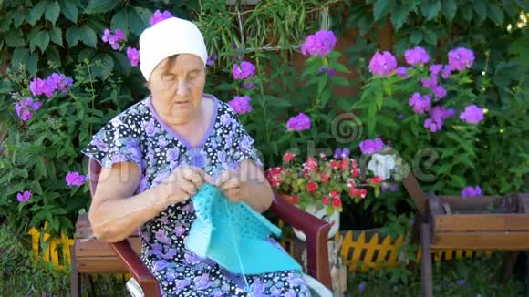 坐在他家外面大街上编织衣服的老妇人视频的预览图