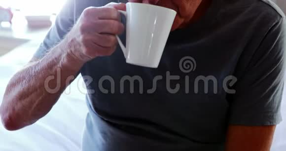 坐在床上喝杯咖啡的老人视频的预览图