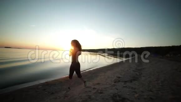 晚上沿着海岸线慢跑运动女孩沿着海滩跑步视频的预览图