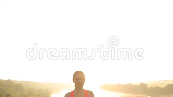 年轻女子剪影在日落时练习瑜伽视频的预览图