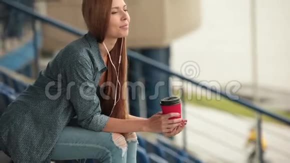 年轻漂亮的女孩坐在街上喝杯咖啡视频的预览图