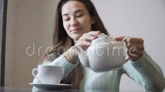 女人把茶从茶壶里倒进杯子里在咖啡馆里视频的预览图
