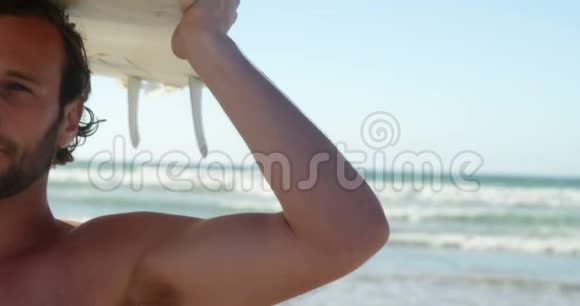 带着冲浪板在沙滩上的年轻人视频的预览图