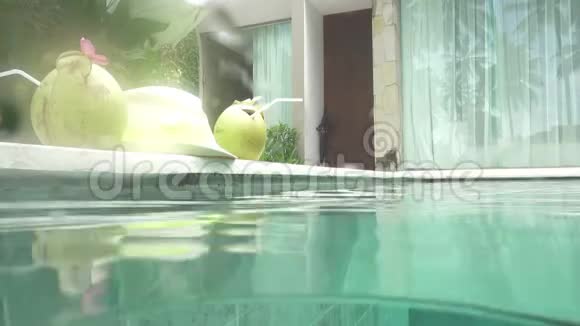 在游泳池里的热带度假胜地身材苗条的年轻女子喝着椰子做的鸡尾酒视频的预览图