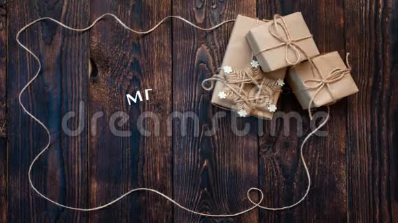 手写白色圣诞快乐动画书法文字在深色木制背景与礼物和视频的预览图