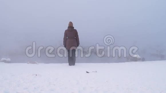 站在雾蒙蒙的河岸上的女人视频的预览图