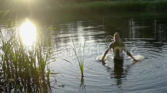 日落时分在池塘里泼水的女孩剪影视频的预览图